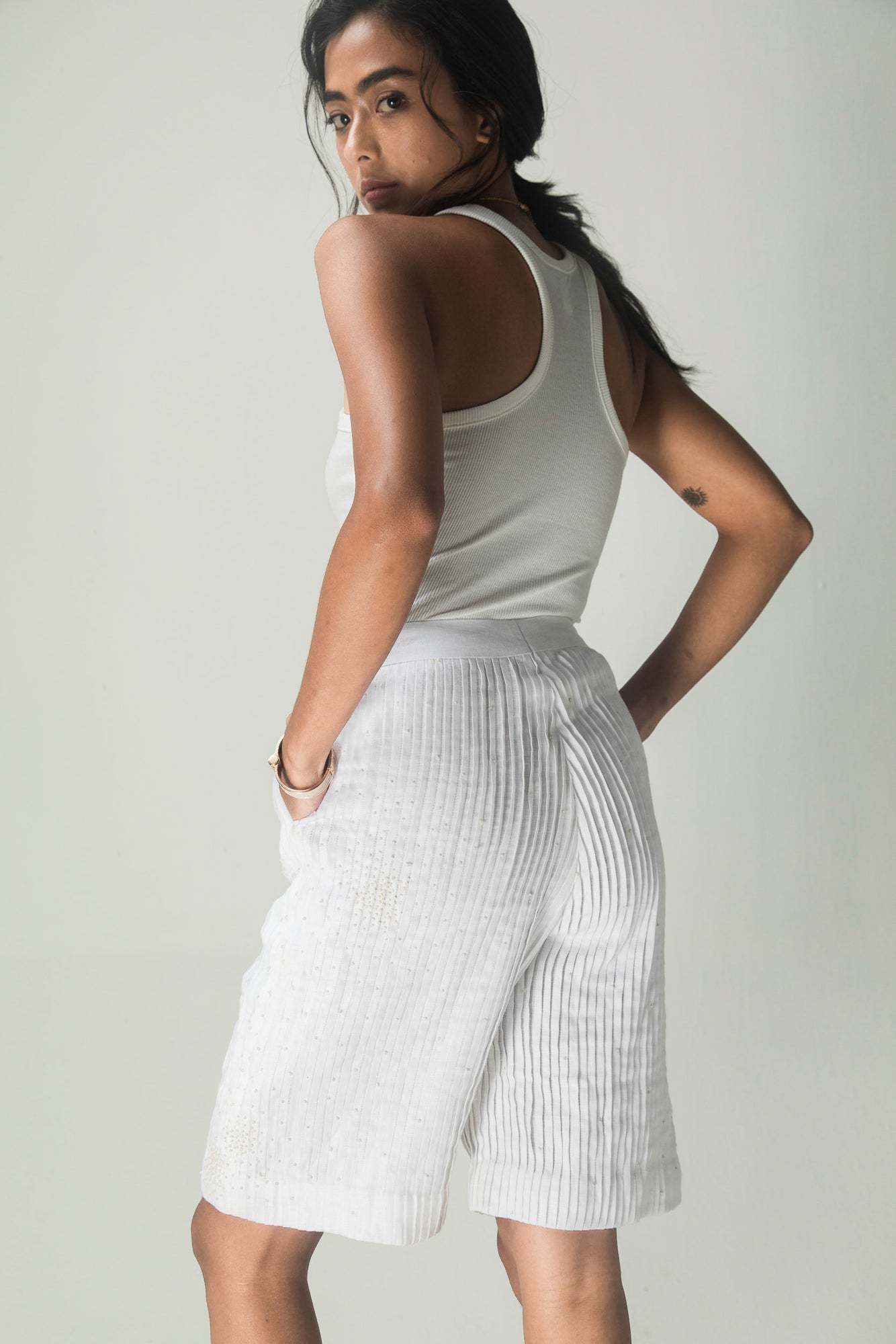 Luxurious white Italian linen shorts with full pleats and delicate white French knots, embodying artisan craftsmanship and elegance