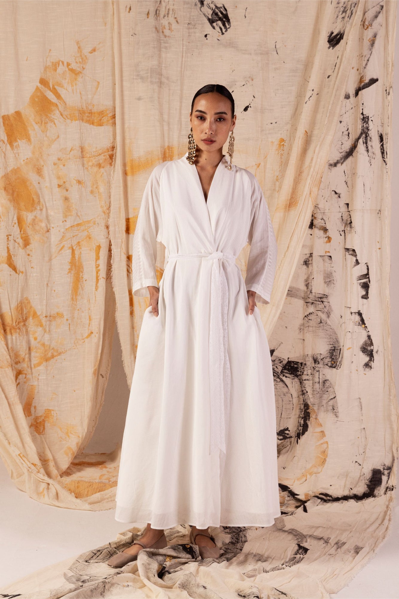 Elegant kimono-style dress in sustainable orange peel fabric, featuring a V-neckline, lace belt, side pockets, and flowing white stripes