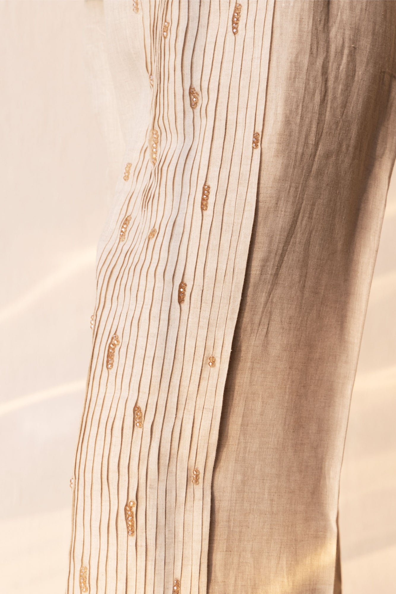 Handcrafted golden pleated trousers in premium fabric, showcasing luxury womenswear with a tailored silhouette and artisan detail