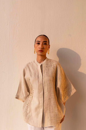 Elegant beige linen shirt with a sleek Mandarin collar, kimono-style pleated sleeves, and subtle crystal embellishments, exuding luxury