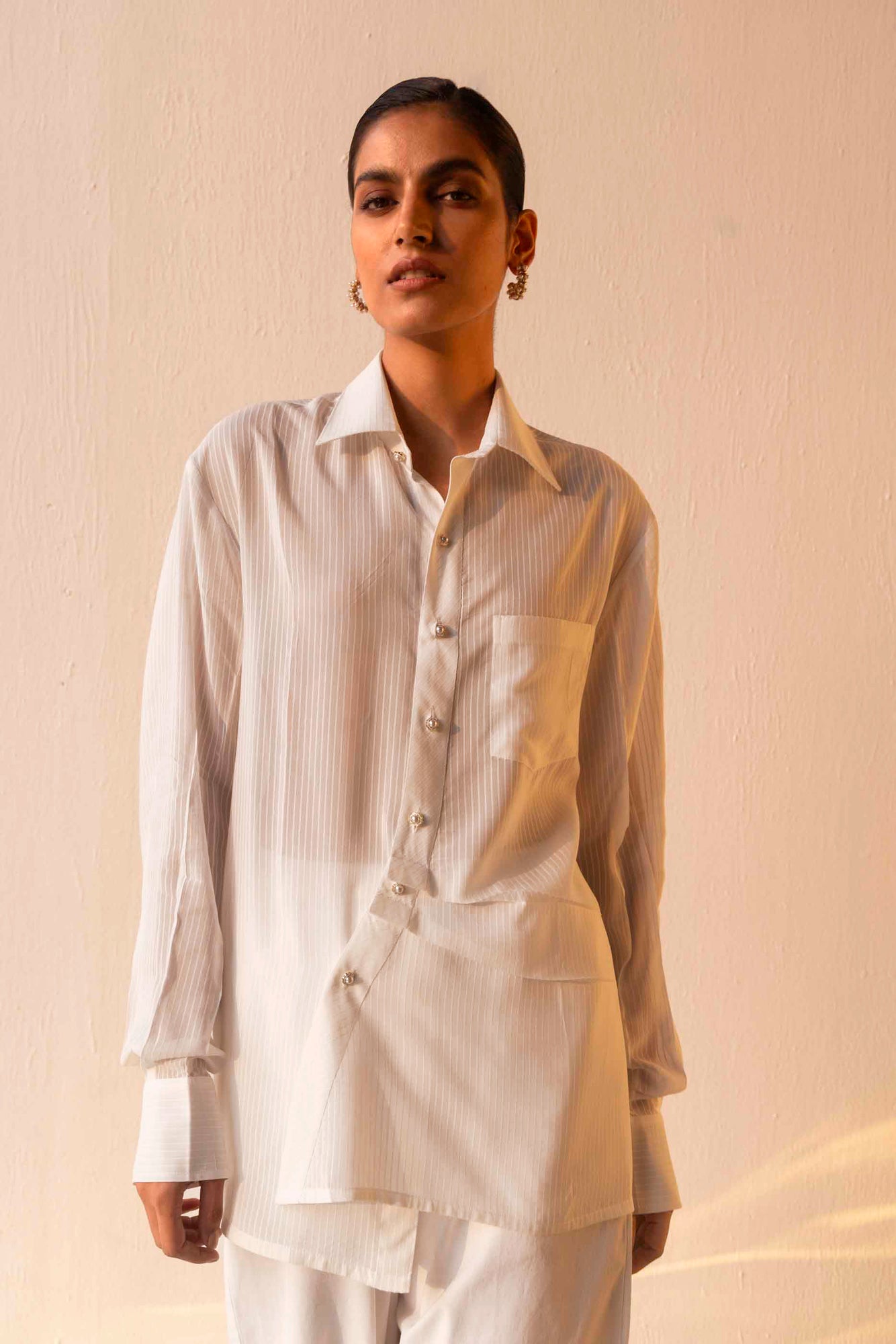 Luxurious orange shirt with a classic collar, pearl buttons, asymmetrical hem, full sleeves, and structured cuffs; artisan-made elegance