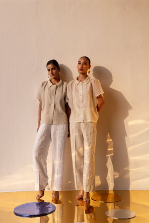 Luxurious white linen trousers with delicate side pleats and sparkling crystal embellishments, featuring an elasticated waist and side pockets