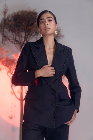 Elegant black denim lycra suit with intricate pearl embroidery and striking red lining, showcasing luxury womenswear craftsmanship