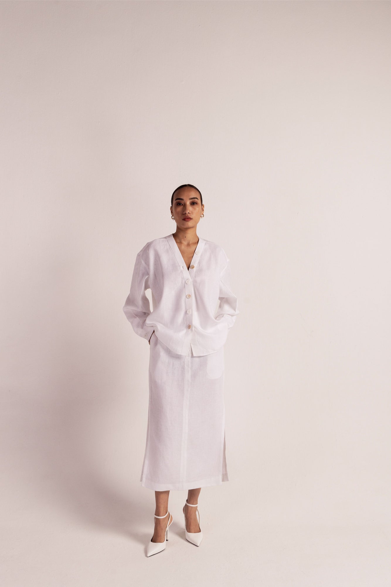 White linen co-ord set with a no-collar shirt, button details, drop shoulders, and a pencil skirt with slits and pockets; artisan-made luxury womenswear
