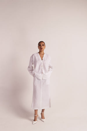 White linen co-ord set with a no-collar shirt, button details, drop shoulders, and a pencil skirt with slits and pockets; artisan-made luxury womenswear