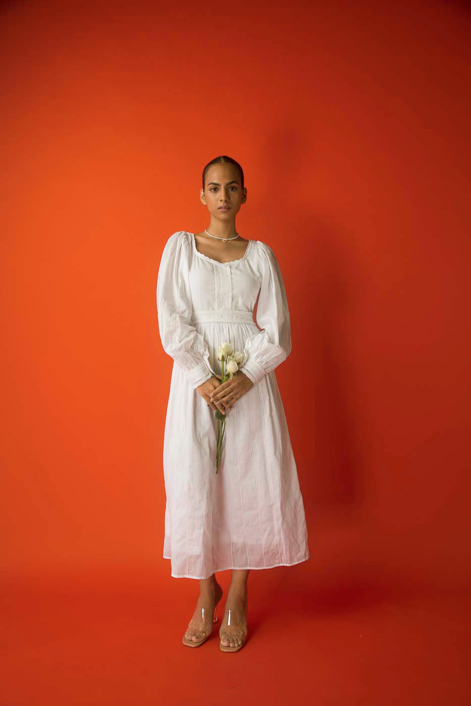 Elegant white midi dress in pure cotton with intricate lace inserts, showcasing luxury womenswear craftsmanship and artisan detailing